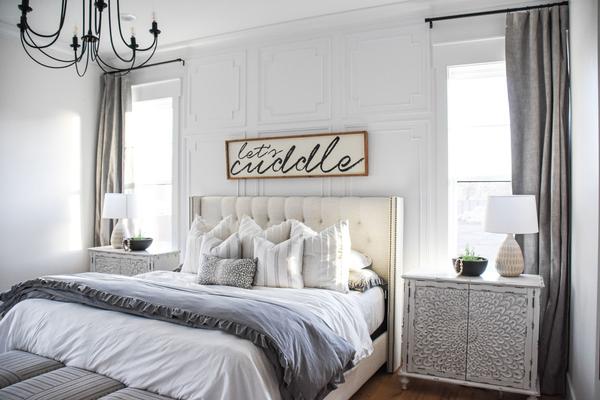 A white bedding with curtains and nightstand 