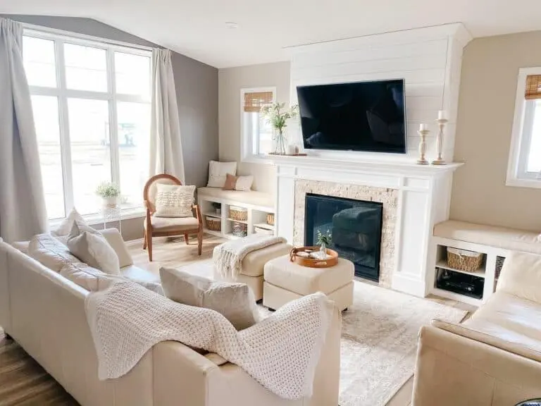 A small living room with tv on the wall and windows and curtain and sofa and cushion 