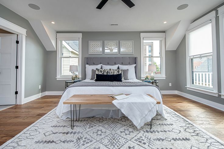 A white and grey bedroom with wooden floor and rug on it 