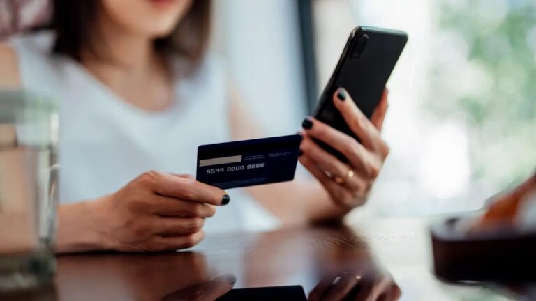 How Credit History Shapes the Cost of Accessing Money a-girl-is-holding-a-credit-card-and-phone-in-her-hands-and-checking-account-number