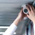 a-man-is-installing-a-camera-in-a-corner-of-a-room-wall