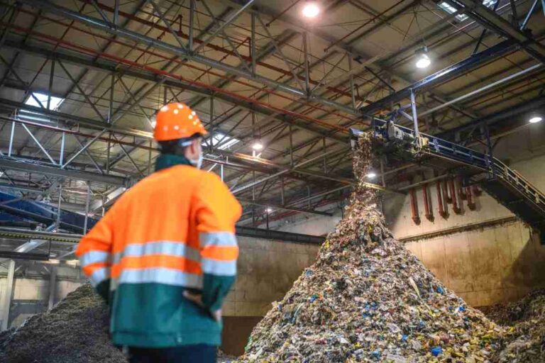The Importance of Eco-Friendly Waste Management Solutions in Virginia a-person-is-standing-infront-of-waste-moved-by-industrial-machinery