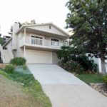 house-with-white-exterior-with-two-car-garage-on-lower-level-and-balcony-accessible-from-the-upper-floor