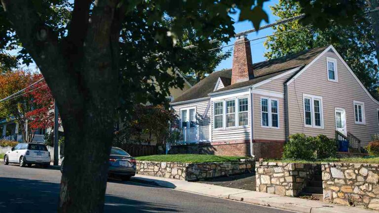 one-and-half-story-house-with-light-colored-siding-and-a-dark-roof-with-numerous-windows-across-the-front-and-back-chinmey