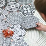 person-placing-decorative-hexagonal-tiles-on-a-floor-surface-and-tile-in-soft-shades-of-blue-grey-white