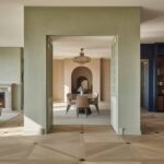 white-sofa-a-fireplace-set-into-a-light-colored-wall-and-large-window-and-the-floor-has-a-textured-patterned-rug