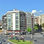 a-city-with-modern-multi-story-apartment-building-several-cars-are-driving-on-the-road