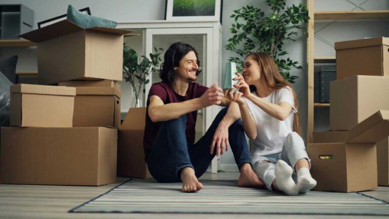 boy-and-girl-sitting-on-floor-of-a-new-home-surrounded-by-packed-cardboad-boxes-and-they-just-moved-in