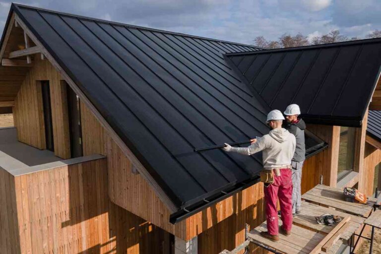 building-with-a-newly-installed-dark-metal-roof-and-two-individual-standing-and-installing-metal-roof