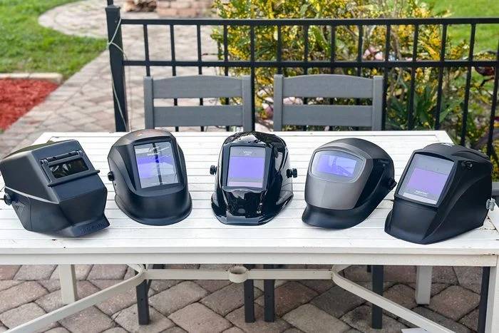 Best Welding Helmets for Weekend Warriors Building Metal Furniture five-different-welding-helmet-placed-side-by-side-on-a-light-colored-outdoor-table