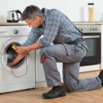 male-appliance-repair-technician-actively-working-on-a-white-front-loading-washing-machine