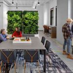 modern-office-interior-the-space-is-bright-with-white-walls-in-middle-there-is-a-large-rectangular-table-two-people-were-standing-and-two-were-sitting