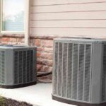 two-outdoor-air-conditioning-condenser-units-placed-on-a-concrete-slb-next-to-a-house