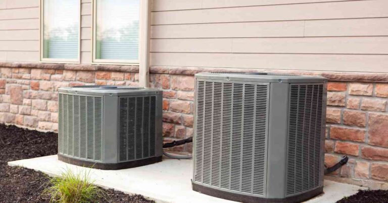 two-outdoor-air-conditioning-condenser-units-placed-on-a-concrete-slb-next-to-a-house