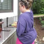 woman-standing-outside-a-house-installing-a-window-box-beneath-she-is-adjusting-bracket-on-the-wall
