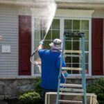 a-person-pressure-washing-the-exterior-windows-of-a-residential-house