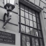 close-up-view-of-the-buildings-facade-featuring-a-large-window-with-multiple-panes-and-two-wall-mounted-lamps
