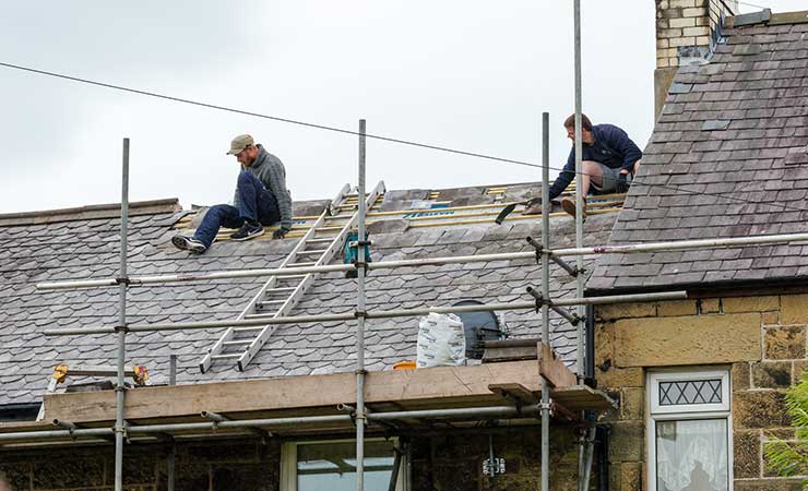 decorative-slate-roof-restoration-taking-place-on-a-residential-property-and-the-two-roofers-working-on-the-slates