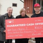 three-people-standing-outdoor-in-a-snowy-environment-holding-a-large-promotional-check