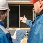 two-constructor-is-standing-and-inspecting-or-reviewing-the-structure-of-a-building-possibly-checking-measurement-or-planning-next-stage-of-construction