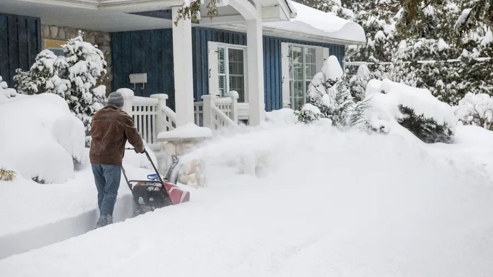 An Image Showing A Person Removing Snow From Front of His House