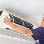 HVAC-technician-performing-maintenance-on-a-wall-mounted-split-air-conditioning-indoor-unit-he-is-focused-on-evaporator-coil-and-internal-component