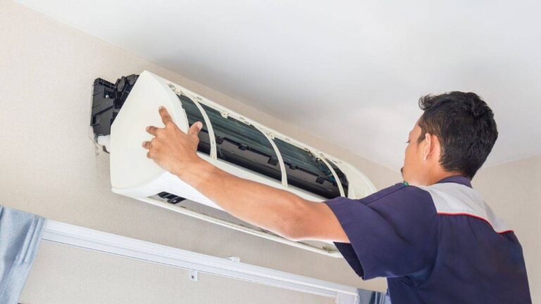 HVAC-technician-performing-maintenance-on-a-wall-mounted-split-air-conditioning-indoor-unit-he-is-focused-on-evaporator-coil-and-internal-component