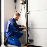 a-man-is-kneeling-next-to-the-doors-track-appearing-to-adjust-or-inspect-a-specific-component-near-the-wall