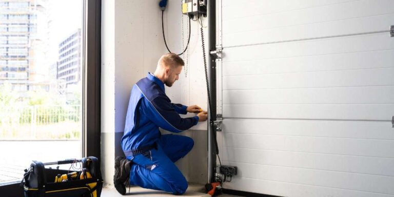 a-man-is-kneeling-next-to-the-doors-track-appearing-to-adjust-or-inspect-a-specific-component-near-the-wall