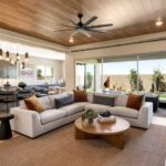 great-room-features-a-modern-anchored-by-a-large-light-colored-L-shaped-sectional-sofa-with-accent-pillow-a-round-wooden-coffee-table-and-a-plush-area-rug