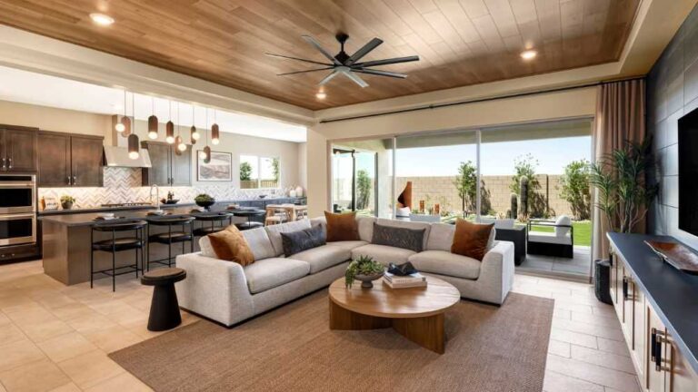 great-room-features-a-modern-anchored-by-a-large-light-colored-L-shaped-sectional-sofa-with-accent-pillow-a-round-wooden-coffee-table-and-a-plush-area-rug