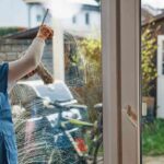 window-cleaning-service-in-progress-a-female-worker-is-cleaning-a-glass-window-pane-using-a-squeengee-and-a-spray-cleaner