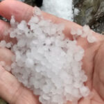 a-person-holding-a-handful-of-small-white-ice-pellets-in-their-palm