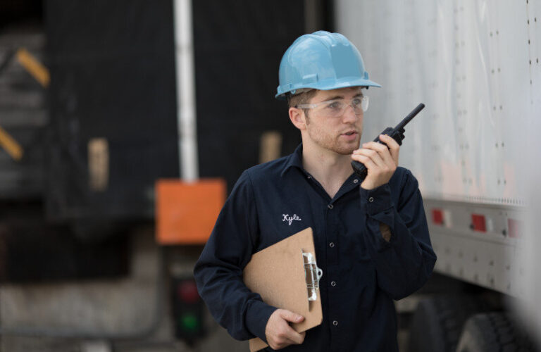 a-worker-wearing-a-blue-safety-helmet-and-communicating-through-a-two-way-radio-he-is-holding-documents