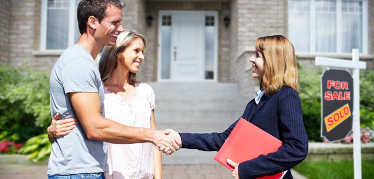 Tailored Mortgages Vs Off-The-Shelf Deals: Which Approach Saves More? a-young-couple-standing-and-smiling-as-they-shake-hands-with-a-blonde-female-real-estate-on-the-right
