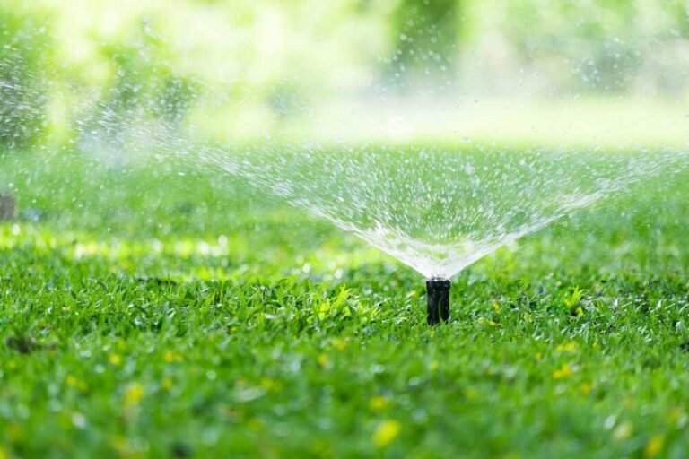 an-outdoor-scene-featuring-an-active-pop-up-lawn-sprinkler-system-watering-a-vibrant-green-grass-lawn