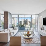 bright-modern-luxury-living-room-the-room-has-a-clean-minimalist-design-with-white-furniture-including-sofas-and-chairs-a-small-round-coffee-table-in-the-center