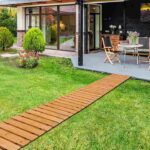 contemporary-backyard-design-featuring-a-long-straight-wooden-garden-pathway-extending-across-the-lawn