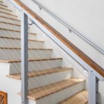 outdoor-staircase-railing-system-features-a-light-colored-stone-or-concrete-treads-with-dark-risers