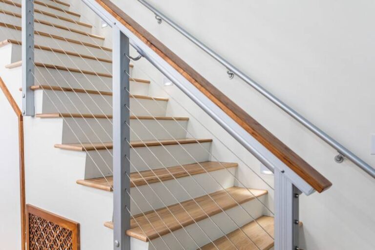 outdoor-staircase-railing-system-features-a-light-colored-stone-or-concrete-treads-with-dark-risers