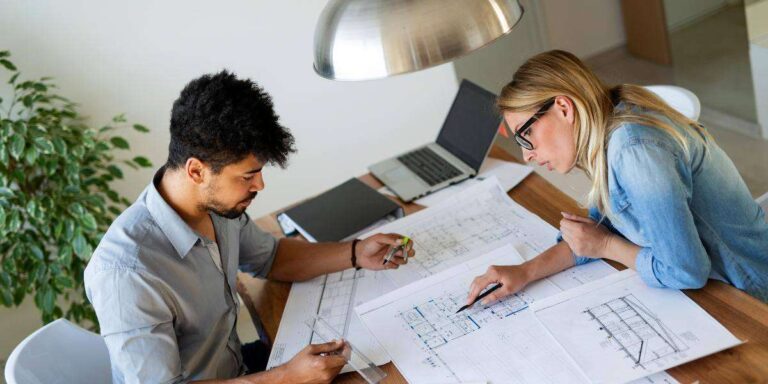 Home Renovation Planning Explained: Architect or No Architect? two-people-looking-over-home-layout-plans-documents-at-a-wooden-table
