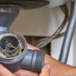 a-clogged-sink-drain-pipe-held-by-a-hand-likely-during-a-plumber-repair