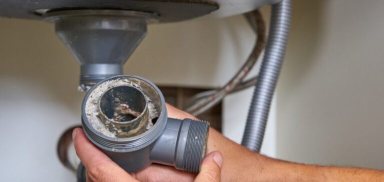 a-clogged-sink-drain-pipe-held-by-a-hand-likely-during-a-plumber-repair