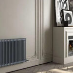 a-dark-gray-horizontal-anthracite-column-radiator-mounted-on-a-light-colored-wall-with-classic-decorative-panel-molding