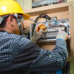 a-electrician-using-a-screwdriver-to-adjust-or-install-wiring-inside-an-open-electrical-breaker-box-mounted-on-a-wall