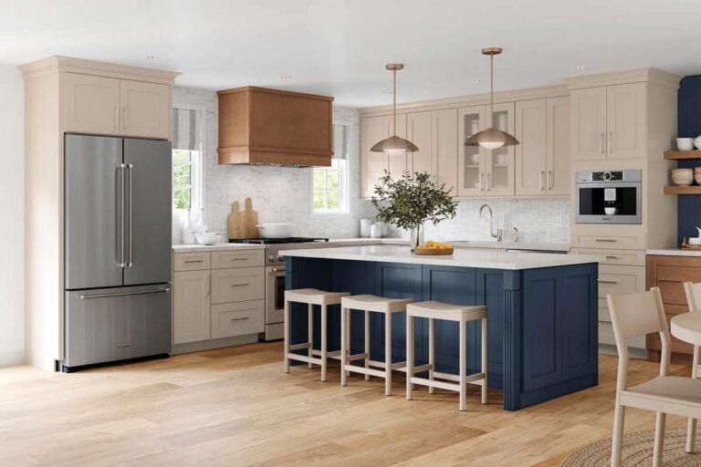 Beyond Catalog Specs: The Case for Custom Kitchen Manufacturing a-large-dark-navy-blue-island-with-thick-white-countertop-sits-in-the-middle-three-backless-wooden-barstools-with-white-frames-stand-tucked-along-the-side