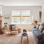 a-living-room-features-white-brick-fireplace-on-the-left-wall-and-glass-coffee-table-with-blue-sofa