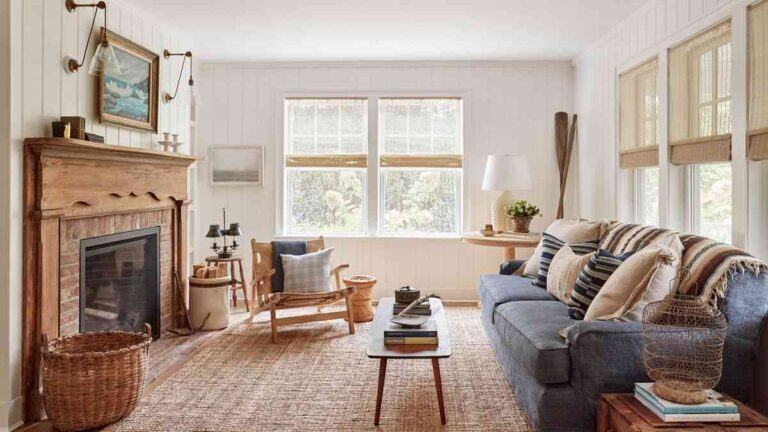 a-living-room-features-white-brick-fireplace-on-the-left-wall-and-glass-coffee-table-with-blue-sofa