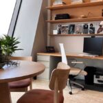 a-long-light-wood-built-in-desk-streches-across-a-wall-featuring-an-computer-setup-and-task-lighting