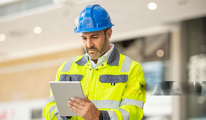 Construction Schedule Optimization: Top Software Picks for 2026 -middle-aged-man-focused-on-a-white-digital-tablet-held-in-his-hands